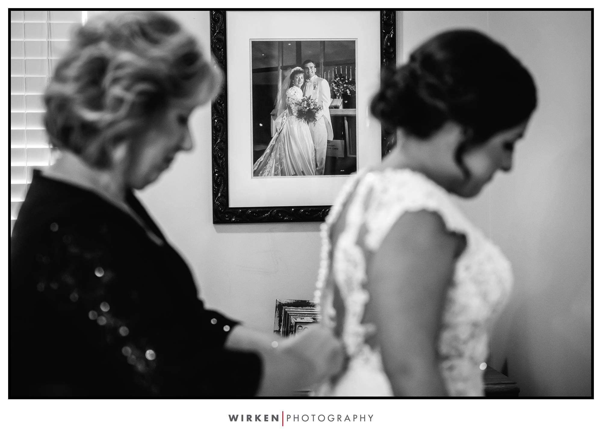 Bride gets into dress with view of parents wedding photo in this kansas city wedding